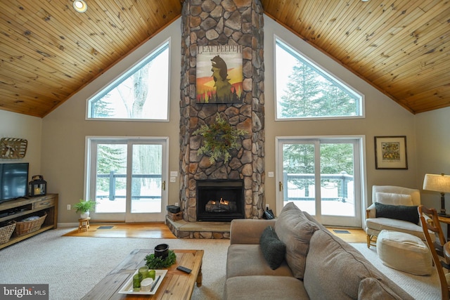 carpeted living area with high vaulted ceiling, a stone fireplace, and wooden ceiling