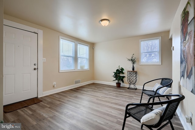 living area with visible vents, baseboards, and wood finished floors