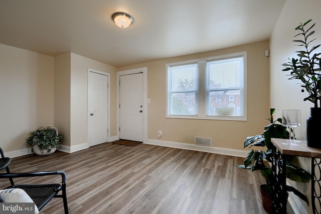 foyer featuring wood finished floors, visible vents, and baseboards