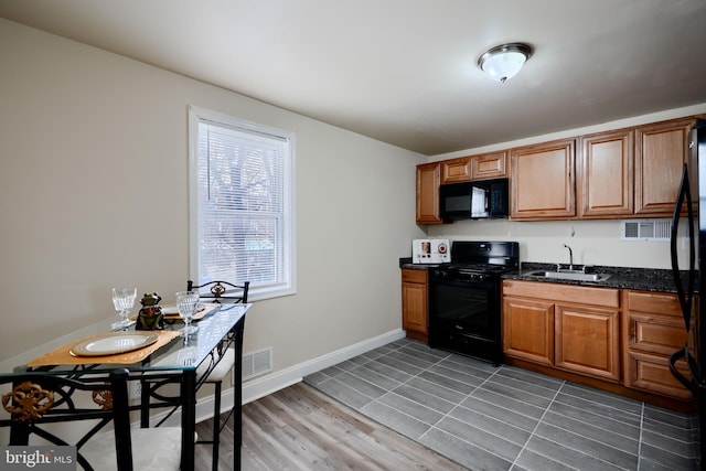 kitchen with a sink, visible vents, baseboards, brown cabinets, and black appliances