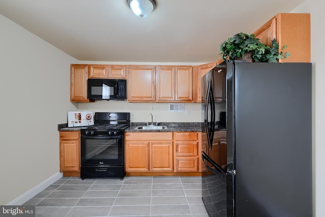 kitchen with light tile patterned floors, baseboards, dark stone counters, black appliances, and a sink