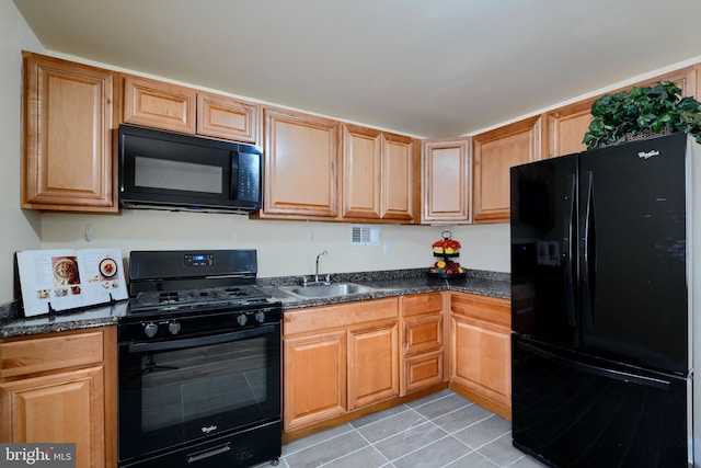 kitchen featuring dark countertops, a sink, black appliances, and light tile patterned floors