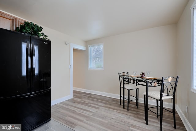 dining space featuring light wood finished floors and baseboards