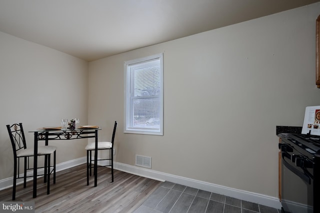 dining room with dark wood-type flooring, visible vents, and baseboards