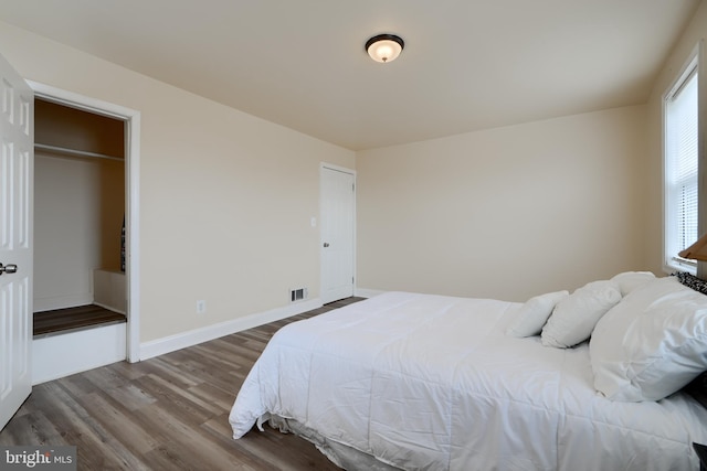 bedroom with visible vents, baseboards, and wood finished floors