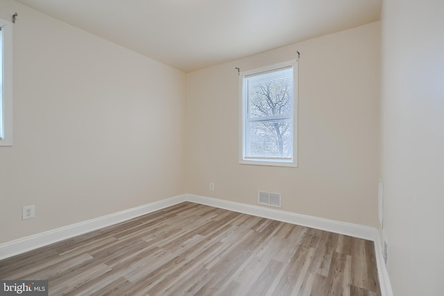 spare room featuring baseboards, visible vents, and light wood-style floors