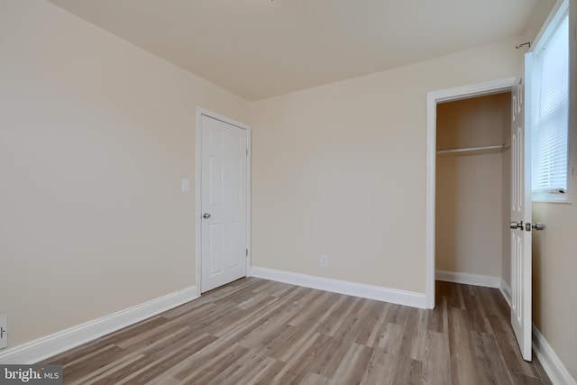 unfurnished bedroom featuring light wood-style floors, a closet, and baseboards