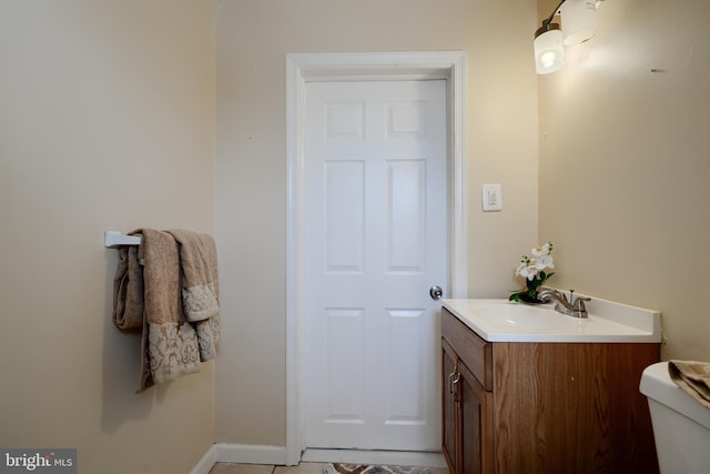 bathroom with baseboards, vanity, and toilet