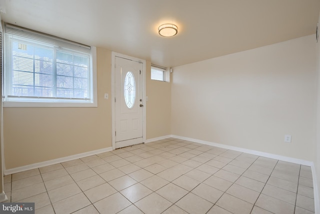 entrance foyer with light tile patterned floors, a healthy amount of sunlight, and baseboards