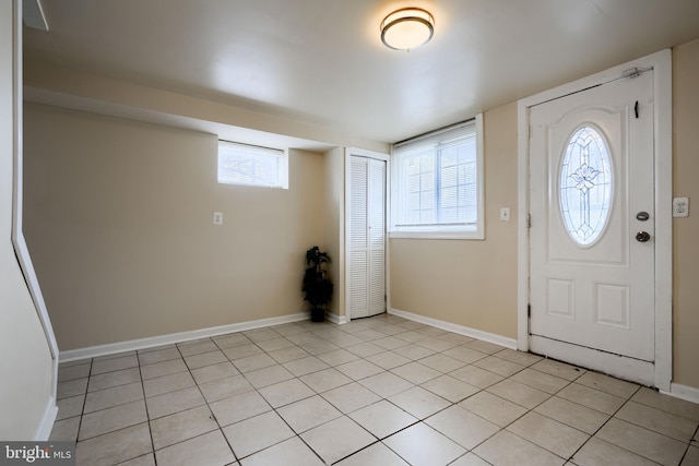 foyer entrance with light tile patterned floors and baseboards