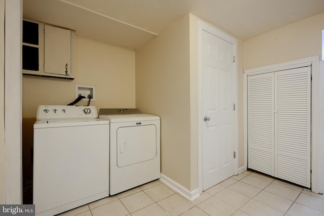 clothes washing area featuring washer and clothes dryer, baseboards, and light tile patterned floors