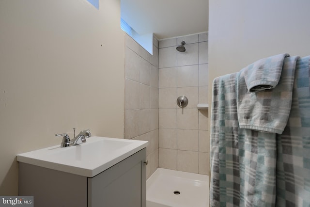 full bath featuring tiled shower and vanity