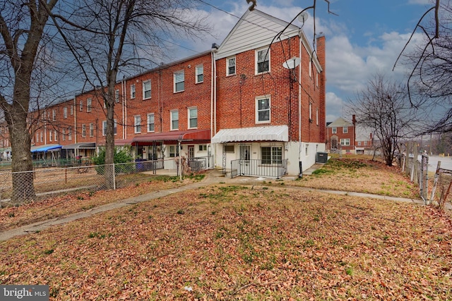 back of property with fence private yard, brick siding, and central AC unit