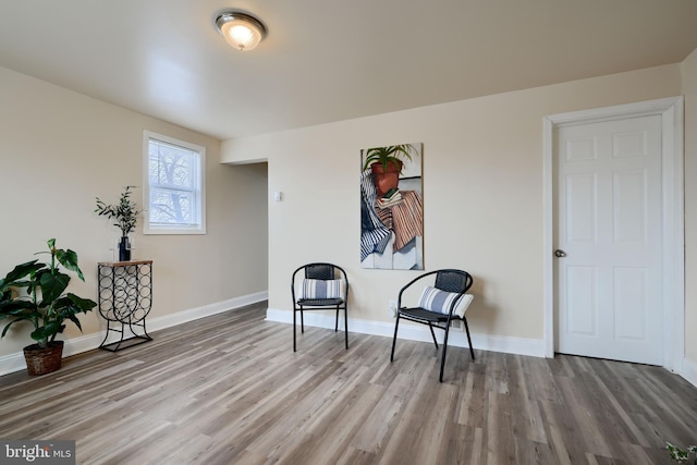 sitting room with baseboards and wood finished floors