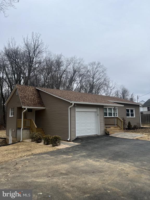 single story home featuring a garage, roof with shingles, and aphalt driveway