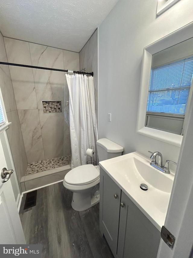 bathroom with visible vents, a stall shower, vanity, a textured ceiling, and wood finished floors