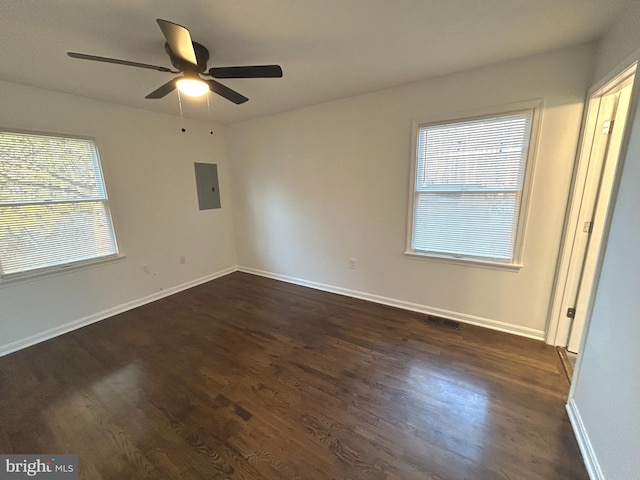 unfurnished bedroom featuring multiple windows, dark wood-style flooring, electric panel, and baseboards