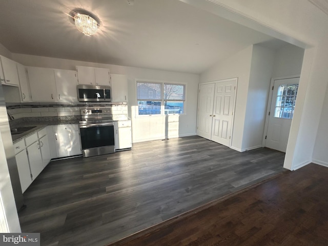 kitchen with white cabinets, decorative backsplash, dark countertops, appliances with stainless steel finishes, and a wealth of natural light