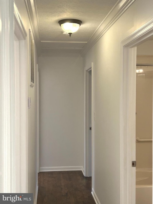 hallway with a textured ceiling, baseboards, dark wood-type flooring, and crown molding