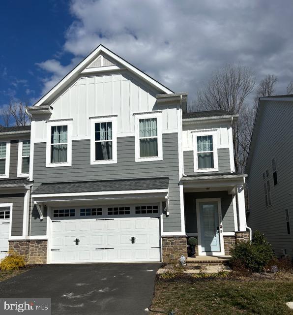 view of front of house featuring board and batten siding, stone siding, driveway, and a garage