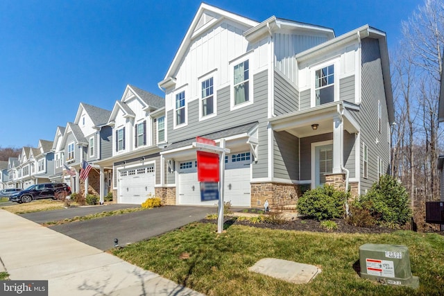 multi unit property with a garage, stone siding, board and batten siding, aphalt driveway, and a residential view