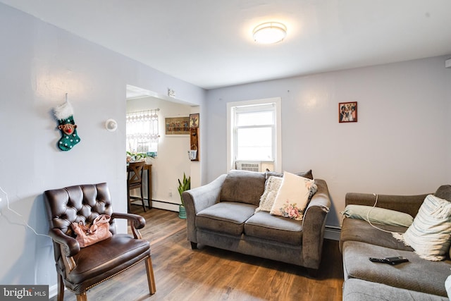 living area with a baseboard radiator, a healthy amount of sunlight, and wood finished floors