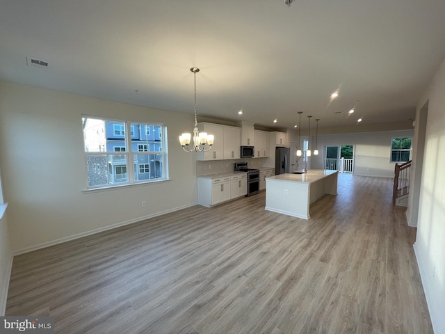 kitchen featuring stainless steel appliances, white cabinetry, open floor plan, hanging light fixtures, and a center island