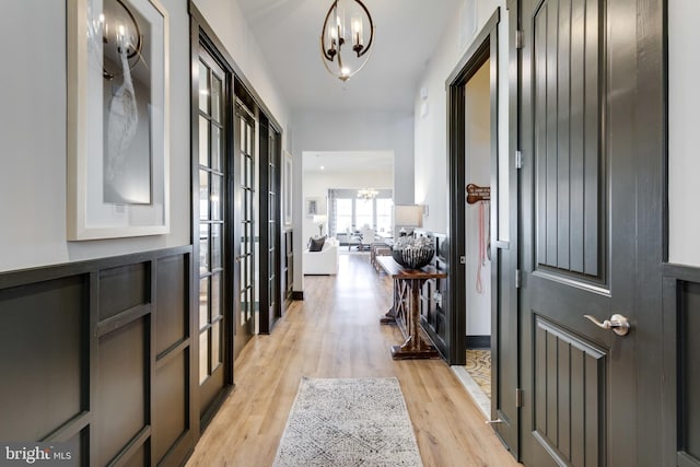 foyer featuring an inviting chandelier, baseboards, and light wood finished floors