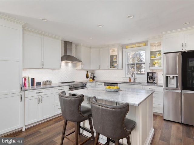 kitchen with dark wood-style floors, wall chimney exhaust hood, appliances with stainless steel finishes, and a sink