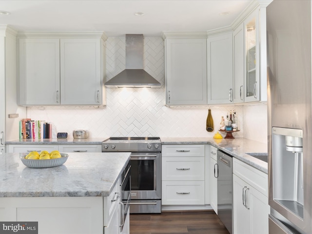 kitchen featuring stainless steel appliances, wall chimney range hood, dark wood-style flooring, and tasteful backsplash