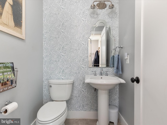 bathroom featuring toilet, baseboards, and a sink