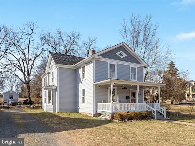 view of front of house with metal roof, a chimney, a porch, and a front yard