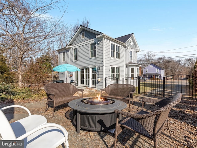 rear view of house featuring metal roof, an outdoor fire pit, and fence