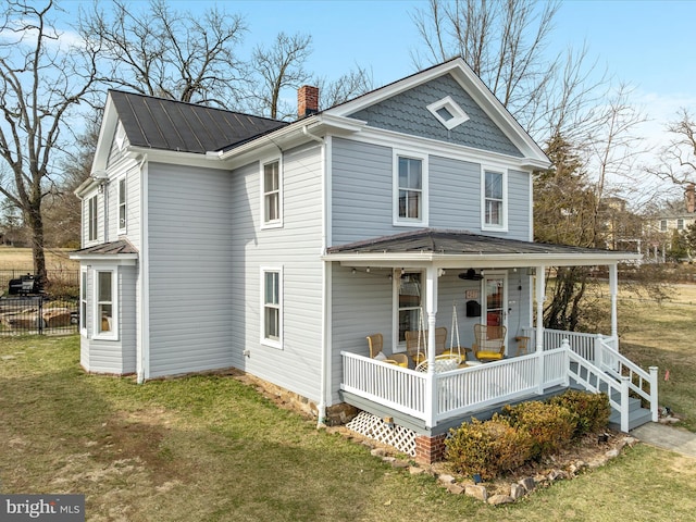 view of front of property featuring a chimney, a porch, metal roof, a standing seam roof, and a front lawn