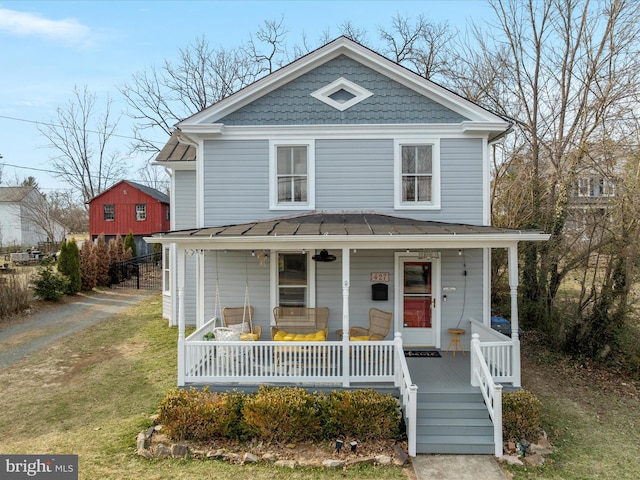 traditional style home with metal roof, a porch, a standing seam roof, and a front lawn