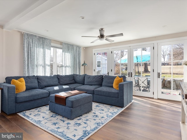 living area with ceiling fan, beamed ceiling, wood finished floors, and french doors