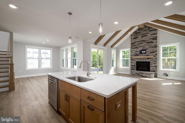 kitchen with a sink, open floor plan, light countertops, hanging light fixtures, and a center island with sink