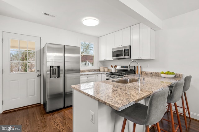 kitchen with light stone counters, appliances with stainless steel finishes, visible vents, and white cabinets