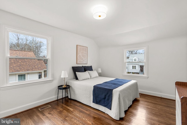 bedroom featuring lofted ceiling, dark wood finished floors, visible vents, and baseboards