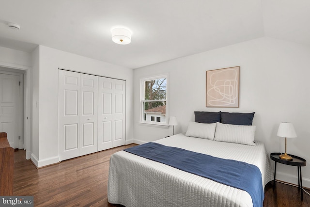 bedroom with a closet, dark wood-style flooring, and baseboards