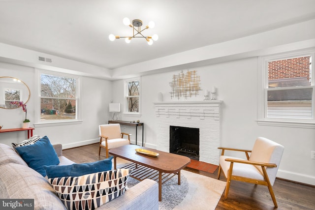 living area with baseboards, a fireplace, visible vents, and dark wood finished floors