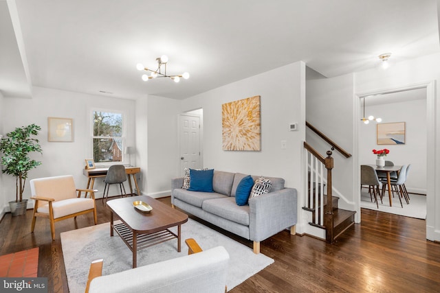 living room featuring stairs, baseboards, dark wood-style floors, and an inviting chandelier