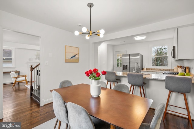 dining space featuring dark wood-style floors, an inviting chandelier, and stairs