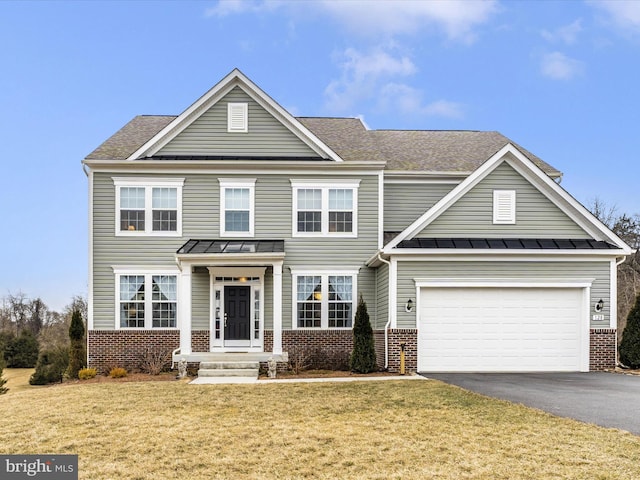 traditional home featuring aphalt driveway, a front yard, a standing seam roof, and brick siding