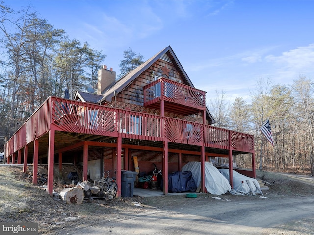 back of property with a chimney and a deck