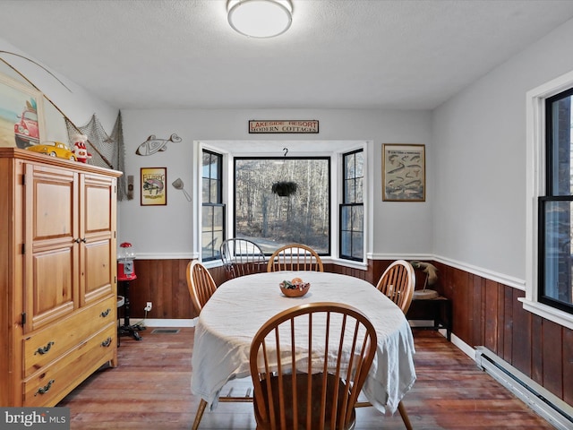 dining space featuring a healthy amount of sunlight, a baseboard radiator, and wainscoting