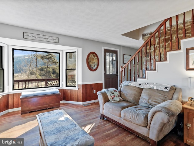 living room with wainscoting, stairway, wood finished floors, a textured ceiling, and wood walls