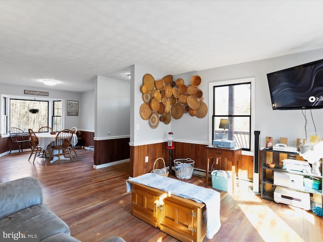 living room with wooden walls, wood finished floors, and wainscoting