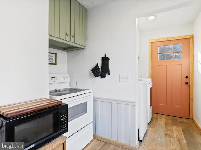 kitchen with light wood finished floors, a wainscoted wall, white electric range, separate washer and dryer, and green cabinetry