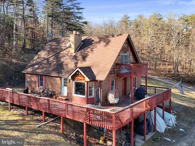 rear view of house featuring a shingled roof, a chimney, and brick siding